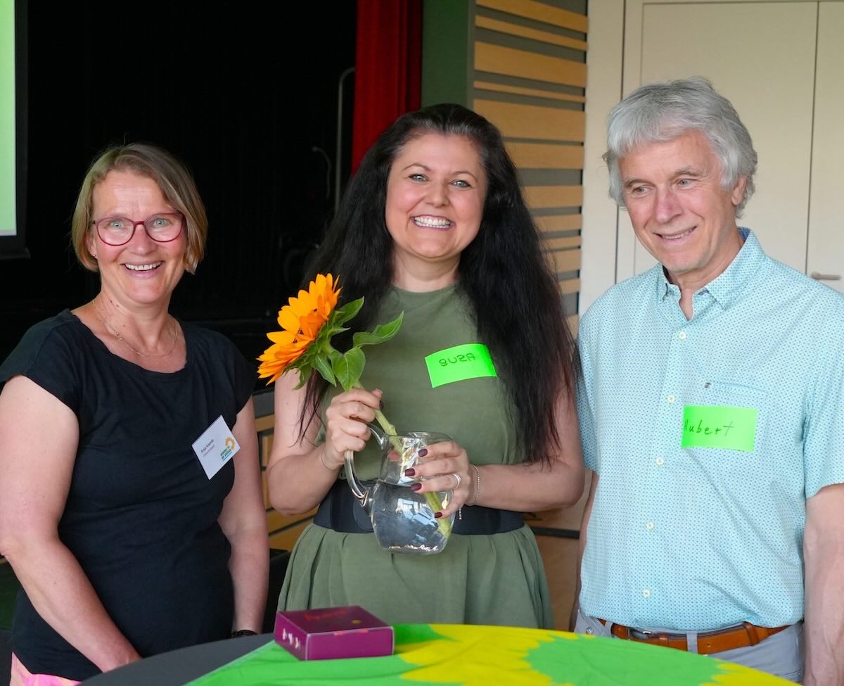 Anja Kiemle und Hubert Laux mit Neu-Mitglied Suzana Breitenherdt in deren Mitte und einer Sonnenblume im Wasserkrug.